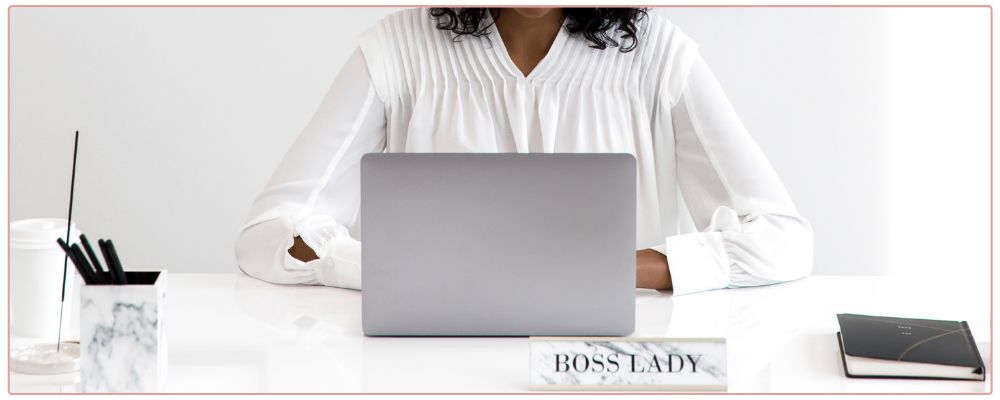 Woman working on her laptop at her desk. Boss Lady Sign on plaque on the desk